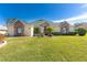 House exterior featuring stone accents, a lush lawn, and a palm tree at 39248 Tacoma Dr, Lady Lake, FL 32159