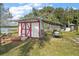 White shed with red trim and a lawnmower at 39645 Turek Ln, Umatilla, FL 32784