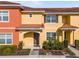 Two-story townhome with orange and yellow exterior, landscaping, and walkway at 8955 Coco Palm Rd, Kissimmee, FL 34747