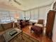 Cozy sunroom with wood floors, a neutral sofa, a patterned rug, and a desk with ample natural light at 106 Gardenia Way, Leesburg, FL 34748