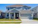 Two-story house with gray siding, stone accents, and a two-car garage at 1304 Silo Dr, St Cloud, FL 34771