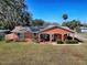 Orange one-story house with a well-maintained lawn and landscaping at 1415 Park Ave, Tavares, FL 32778