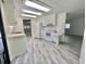 Functional kitchen with white appliances, white cabinets, and modern gray flooring for efficient living at 149 Royal Palm Dr, Leesburg, FL 34748