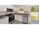 Modern kitchen featuring stainless steel appliances, granite countertops, and sleek white cabinetry, and a view to the yard at 15323 Sw 25Th Pl, Ocala, FL 34482