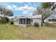 Backyard view showing the home's rear exterior, enclosed patio, and manicured lawn at 1613 Cherry Hill Rd, The Villages, FL 32159