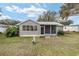 Exterior view of the backyard with a screened lanai, well-maintained lawn, and mature trees at 1613 Cherry Hill Rd, The Villages, FL 32159