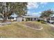 Exterior shot of the home with a two-car garage, charming landscaping, and mature trees at 1613 Cherry Hill Rd, The Villages, FL 32159