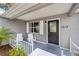 A cozy front porch featuring stylish seating, a decorative front door with house number, and fresh landscaping at 1613 Cherry Hill Rd, The Villages, FL 32159