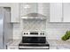 A well-lit kitchen featuring a stainless steel range hood, a ceramic backsplash, and granite countertops at 1613 Cherry Hill Rd, The Villages, FL 32159