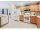 Well-equipped kitchen featuring wooden cabinets, white appliances, and tile flooring at 16814 Se 80Th Bellavista Cir, The Villages, FL 32162