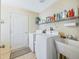 Functional laundry room with washer, dryer, utility sink, storage shelves, and tile flooring at 16814 Se 80Th Bellavista Cir, The Villages, FL 32162
