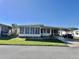 Charming manufactured home featuring a sunroom, carport, and well-maintained lawn at 188 Hibiscus Way, Leesburg, FL 34748