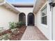 Welcoming entryway with a brick walkway, arched doorway, and manicured garden beds at 5312 Meadow Hill Loop, Lady Lake, FL 32159