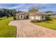Beautifully landscaped front yard and long brick driveway leading to a well-maintained home at 5312 Meadow Hill Loop, Lady Lake, FL 32159