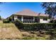 House back view, showcasing a screened porch, fenced yard, and sloped lawn at 5312 Meadow Hill Loop, Lady Lake, FL 32159