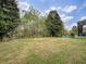 Expansive green backyard featuring lush trees, a black fence, and a glimpse of a sparkling pool at 5812 Ansley Way, Mount Dora, FL 32757