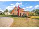 Yellow house with red trim and brick chimney, paved driveway at 7206 Earlwood Ave, Mount Dora, FL 32757