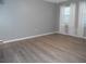 Sunlit bedroom featuring stylish wood-look floors, neutral walls, and large windows with white curtains at 723 Perkins St # 104, Leesburg, FL 34748