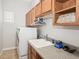 Laundry room featuring a sink, washer, dryer, and wooden storage cabinets at 1029 Juliette Blvd, Mount Dora, FL 32757