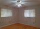 Bright bedroom with wood floors, ceiling fan, and two windows with curtains at 10337 Se 176Th St, Summerfield, FL 34491