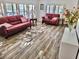 Sunlit living room with leather sofas and wood-look floors at 105 Royal Palm Dr, Leesburg, FL 34748