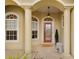 Inviting front porch with decorative columns, a bright red door, and a cozy wicker chair at 12163 Se 176Th Loop, Summerfield, FL 34491