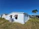 Another side view of a white single-wide manufactured home with landscaping at 128 Lake Hazel Dr, Winter Haven, FL 33884