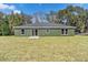 The home's green exterior is visible from a grassy backyard, complete with a sliding glass door at 1511 Moss Ave, Leesburg, FL 34748