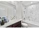 Modern bathroom featuring sleek vanity, sink, faucet, and tub-shower with white marble-like tiling at 1511 Moss Ave, Leesburg, FL 34748