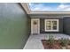 Inviting front porch features a neutral door with wreath, complementing the exterior paint and landscaping at 1511 Moss Ave, Leesburg, FL 34748