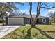 Charming one story home featuring a two-car garage and a well-manicured lawn with a large shade tree at 1511 Moss Ave, Leesburg, FL 34748