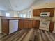 Kitchen with wood cabinets, white appliances and flooring at 16154 Magnolia Hill St, Clermont, FL 34714