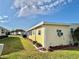 Side view of yellow single story home with landscaping and yard at 180 Hibiscus Way, Leesburg, FL 34748