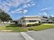 Side view of a yellow single story home showcasing manicured lawn at 180 Hibiscus Way, Leesburg, FL 34748