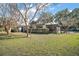 Home exterior featuring a spacious screened in porch, well-maintained yard, mature trees, and concrete driveway at 24450 Ne 127Th St, Salt Springs, FL 32134