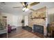 Cozy living room featuring a brick fireplace, wood floors, and a ceiling fan with light fixture at 24450 Ne 127Th St, Salt Springs, FL 32134