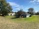 View of the home's back and side, showcasing a large backyard and neighborhood context at 2613 Crest Dr, Haines City, FL 33844