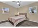 Cozy bedroom with a ceiling fan, a bed with striped bedding, two windows, and dark floors at 2667 Northland Rd, Mount Dora, FL 32757