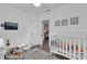 White-walled Bedroom with a crib, TV, bench, and a doorway with a view into another room at 2667 Northland Rd, Mount Dora, FL 32757