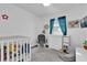 Bright Bedroom featuring a crib, gray rocking chair, changing table, and an accent window at 2667 Northland Rd, Mount Dora, FL 32757