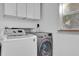 Laundry room featuring a washer and dryer, overhead cabinets, and a window at 2667 Northland Rd, Mount Dora, FL 32757