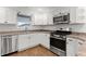 Well-lit kitchen featuring stainless steel appliances, wood laminate floor, and white cabinets at 284 Pelchat Pl, The Villages, FL 32163