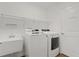 Bright laundry room with white washer, dryer, utility sink, and storage shelf at 284 Pelchat Pl, The Villages, FL 32163