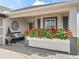 Covered porch with red flowers, bench, and rocking chairs at 2987 Schoenacher St, The Villages, FL 32163