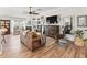 Spacious living room featuring hardwood floors, a leather sofa, and a large TV at 2987 Schoenacher St, The Villages, FL 32163