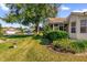 Well-manicured front lawn with lush landscaping and mature trees on a sunny day at 3001 Saint Thomas Ln, The Villages, FL 32162