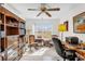 Well-lit home office with a ceiling fan, desk, bookshelves, and a sunny window at 3001 Saint Thomas Ln, The Villages, FL 32162