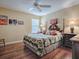 Bedroom with a ceiling fan, wood floors, and a patterned bedspread at 320 Rhapsody Path, The Villages, FL 32162