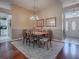 Formal dining room with a wood table, patterned rug, wainscotting, chandelier, and archway leading to foyer at 320 Rhapsody Path, The Villages, FL 32162