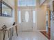 Bright foyer features a white front door with decorative glass, neutral tile flooring, and a stylish accent table at 320 Rhapsody Path, The Villages, FL 32162